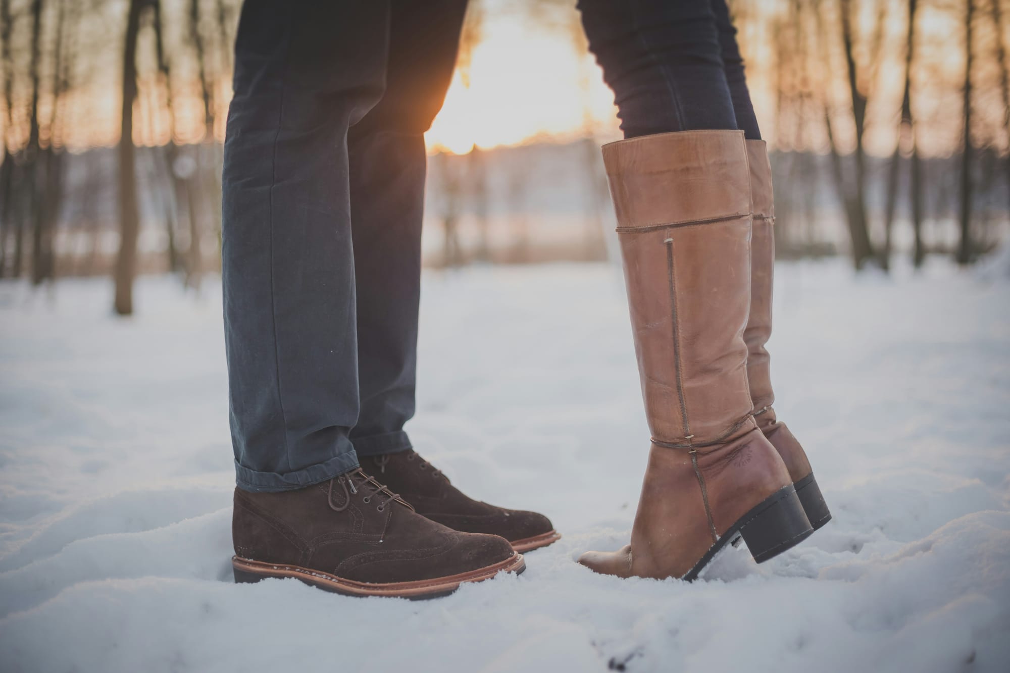 Person wearing brown suede ankle boots and person wearing knee high leather tan boots 